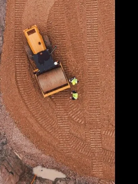 Vista aérea de movimiento de suelos con compactadora